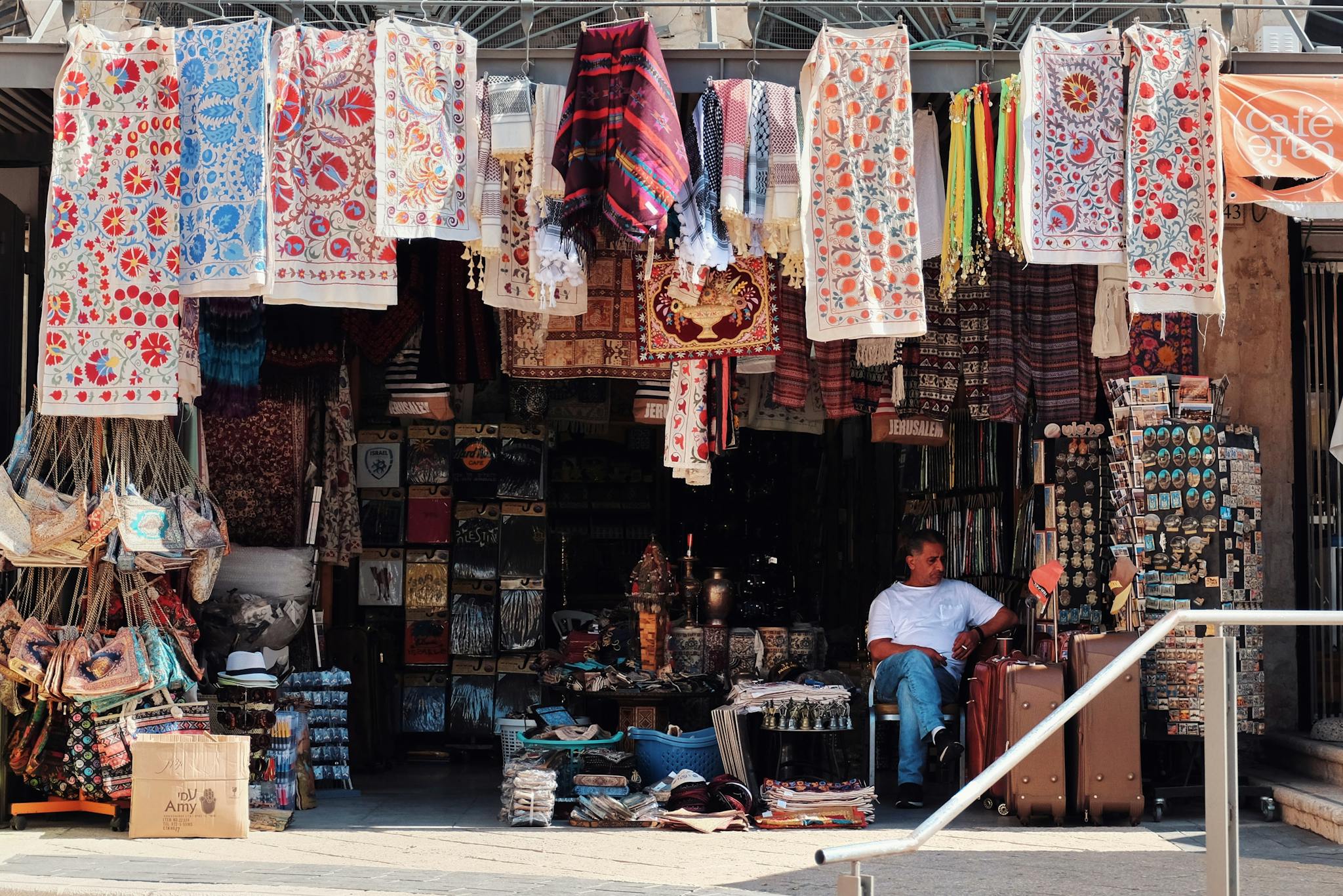 A bustling market stall displaying colorful tapestries and souvenirs in an outdoor bazaar setting.